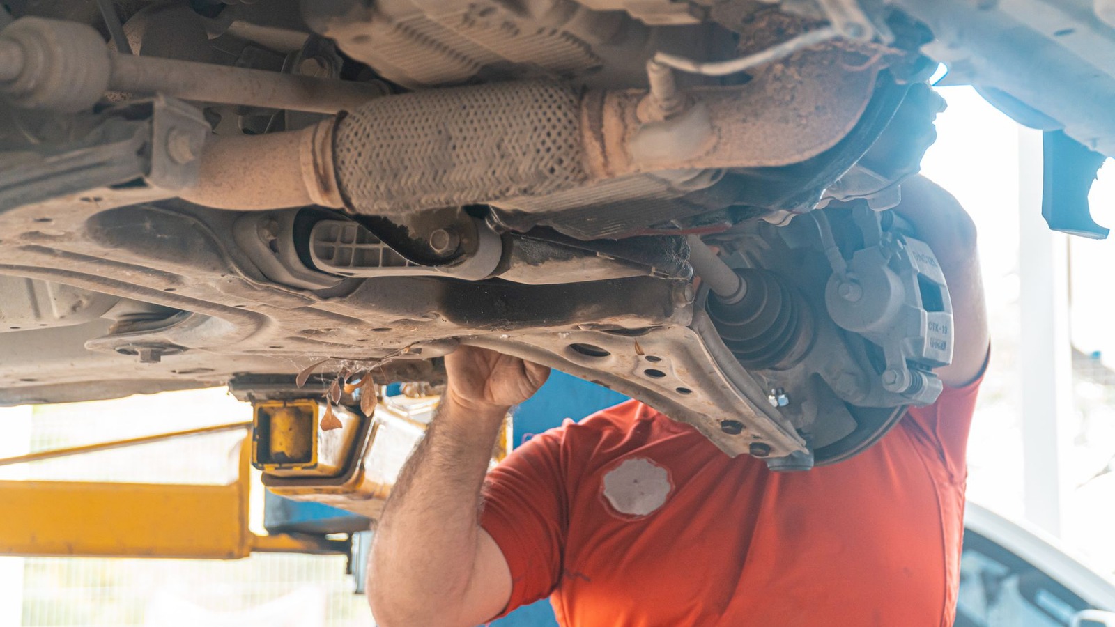 A technician working beneath a raised vehicle on a workshop lift