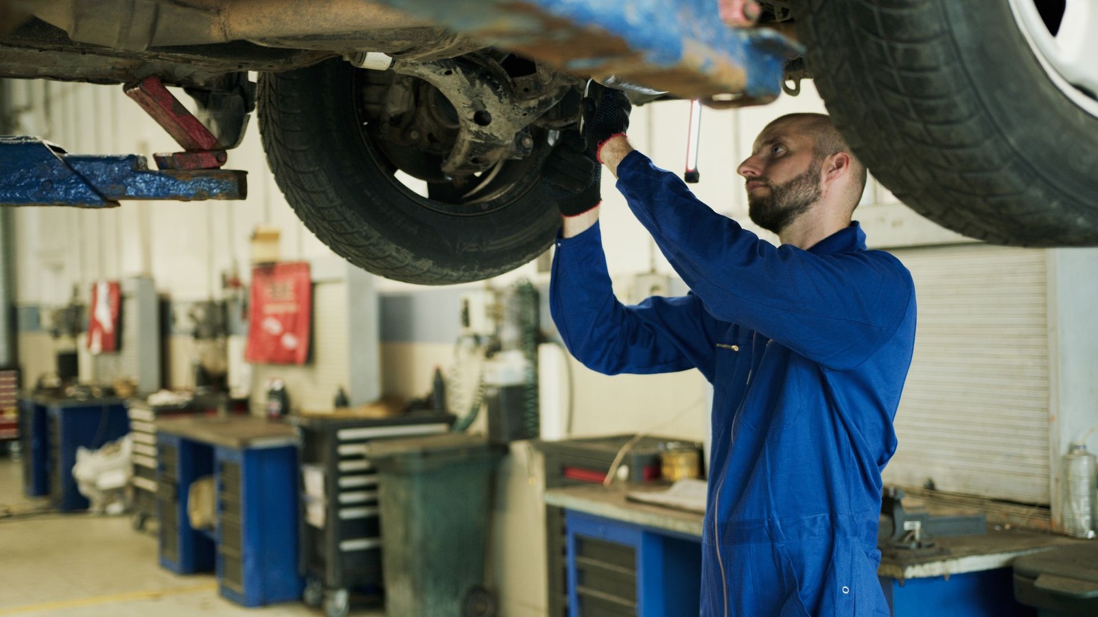 A mechanic inspecting the underside of a vehicle raised on a lift