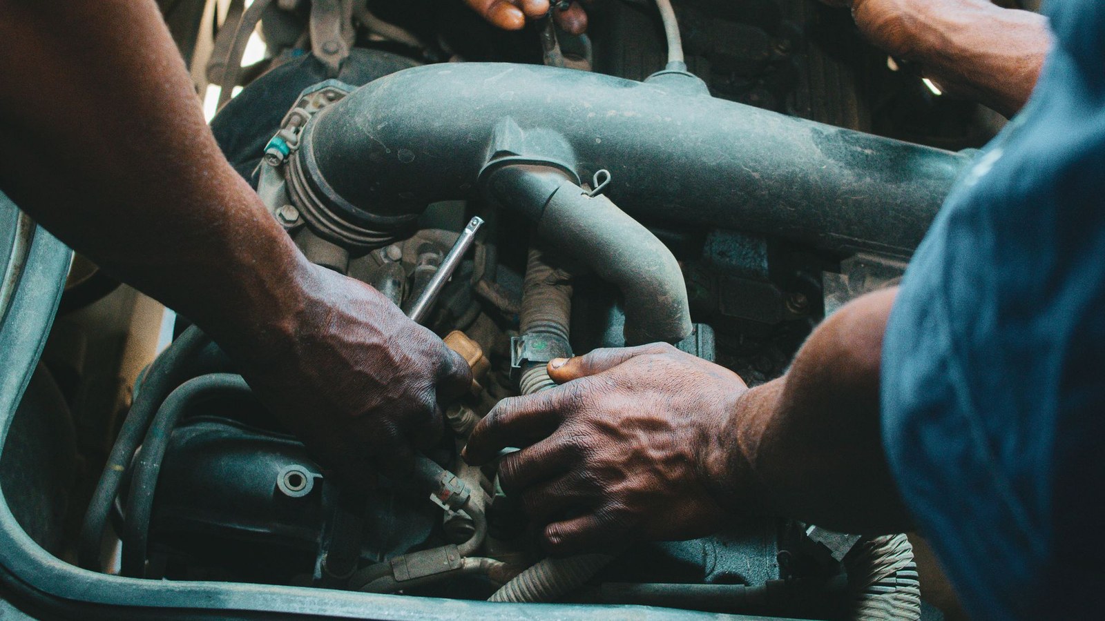 Two mechanics working on an engine bay with tools