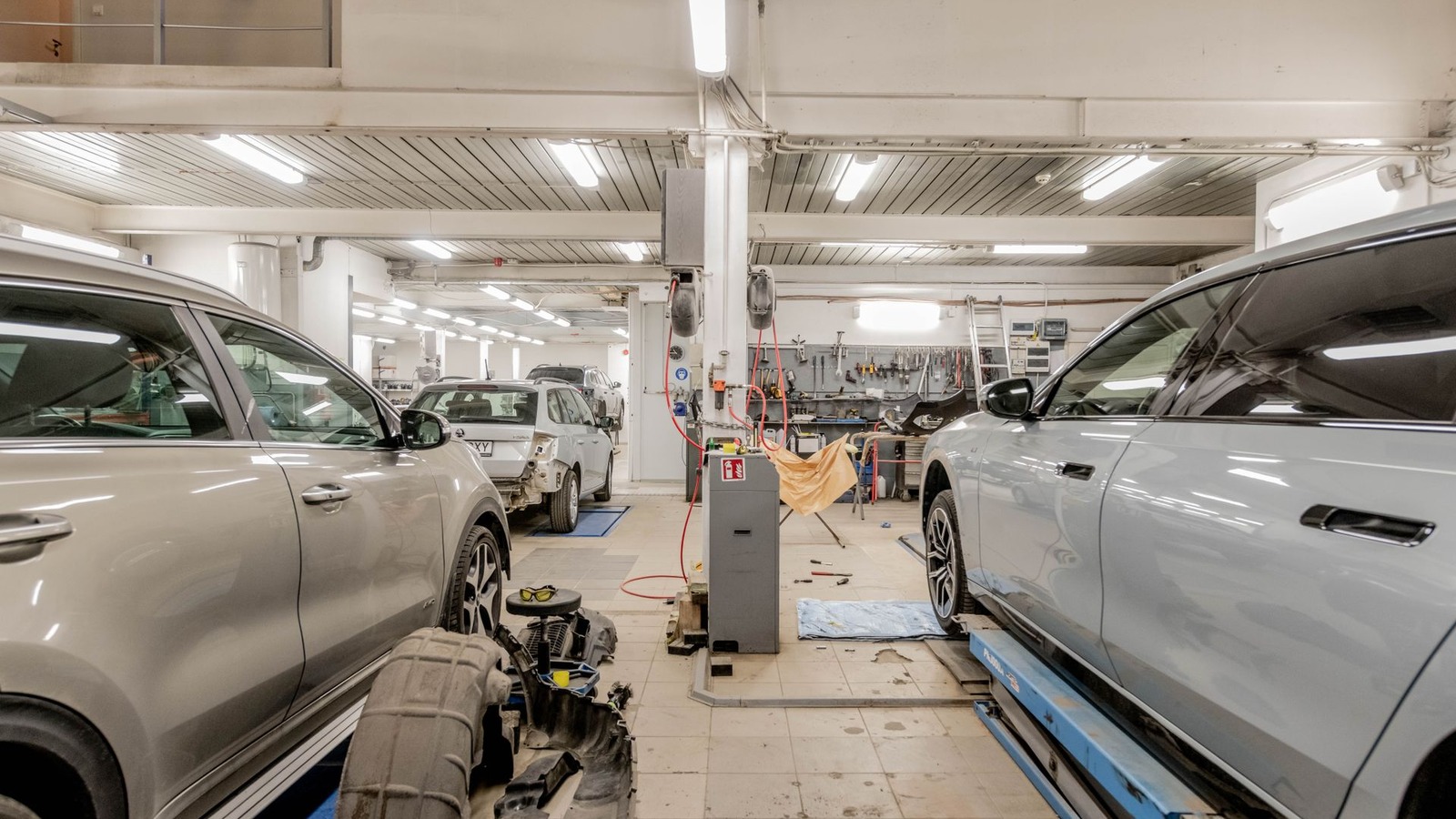 Cars raised on lifts along the bays of a busy vehicle repair workshop