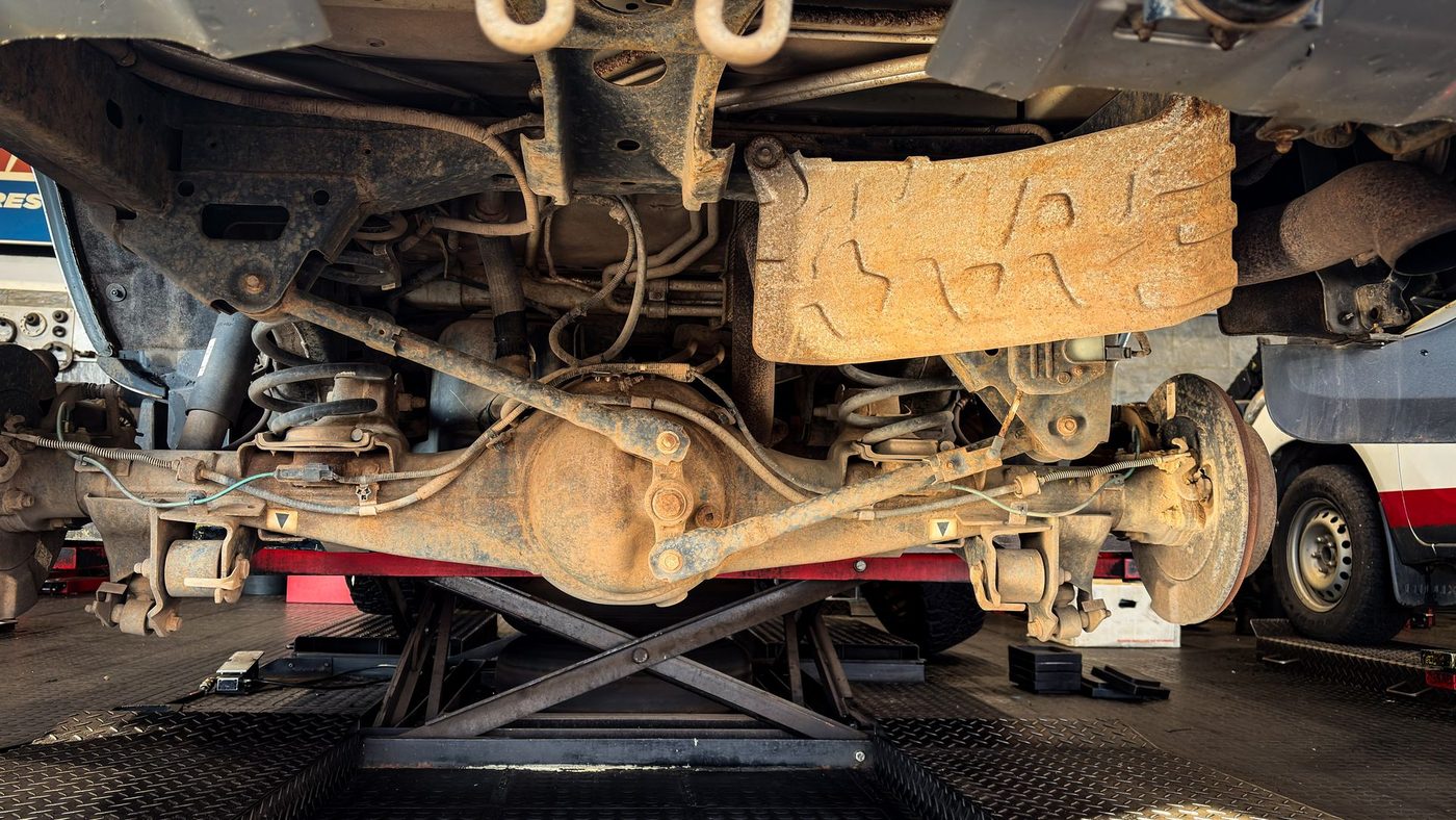 The underside of a raised vehicle showing suspension, exhaust and driveline components