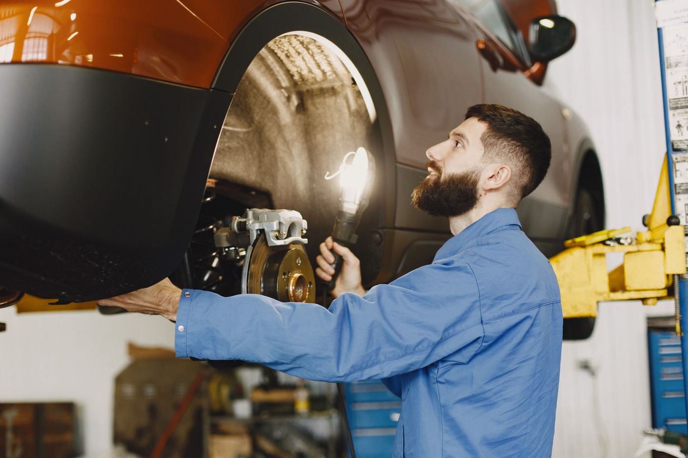 A mechanic examining a vehicle's brake assembly with the wheel removed
